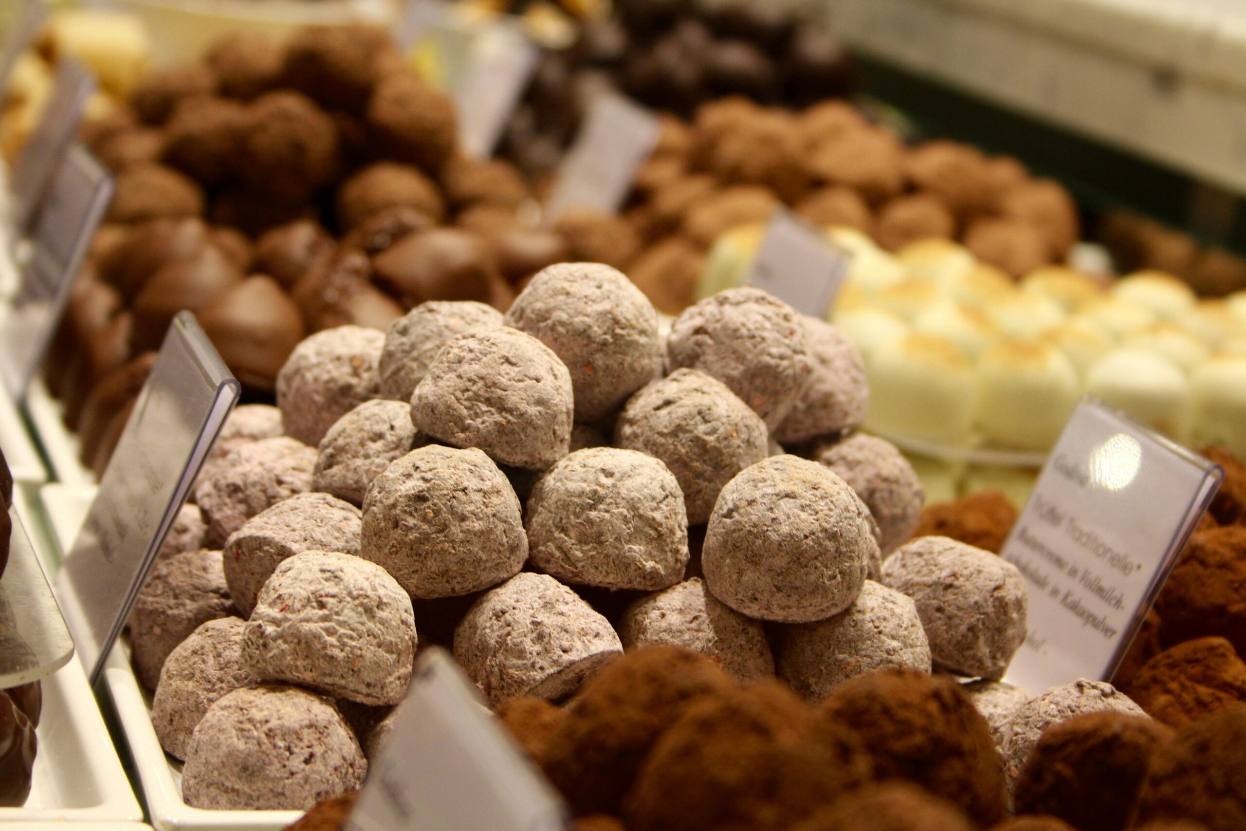 A variety of delicious chocolate truffles on display in a confectionery store with labels.